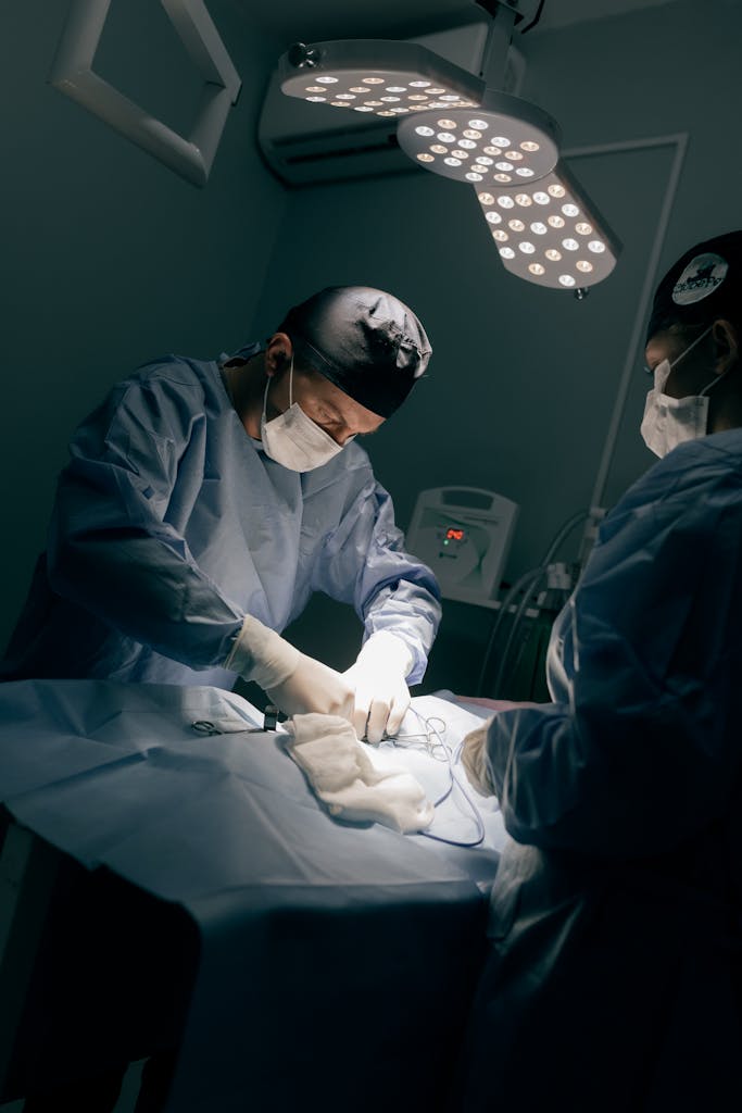 Medical team in operating room performing surgery under professional lighting.